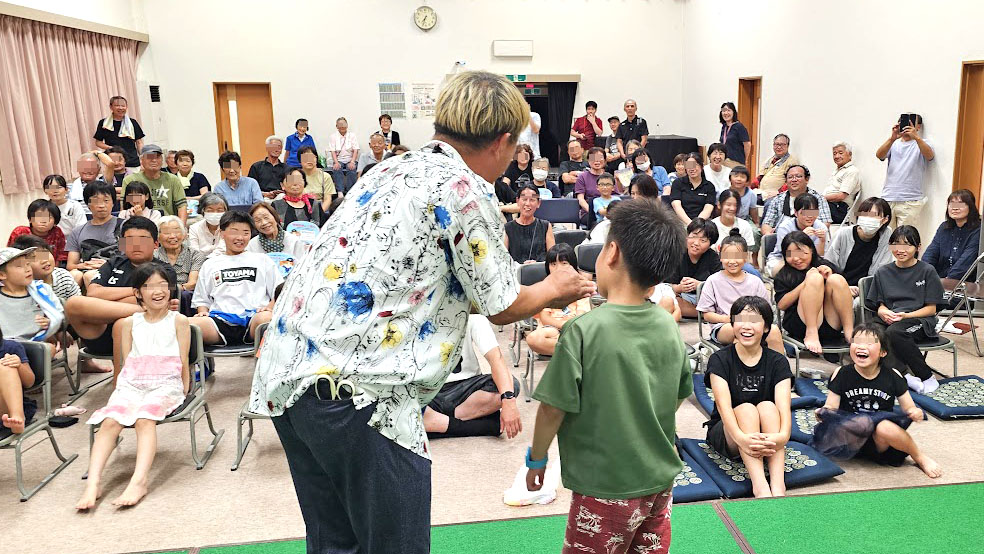 納涼祭マジックショー時間 屋内会場で子どもと観客が笑顔で交流する場面
