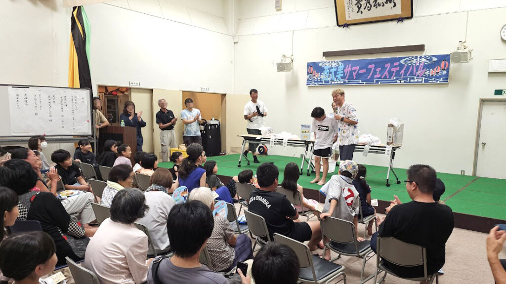 納涼祭マジックショー時間 屋内会場で抽選会を進行し観客と盛り上がる様子