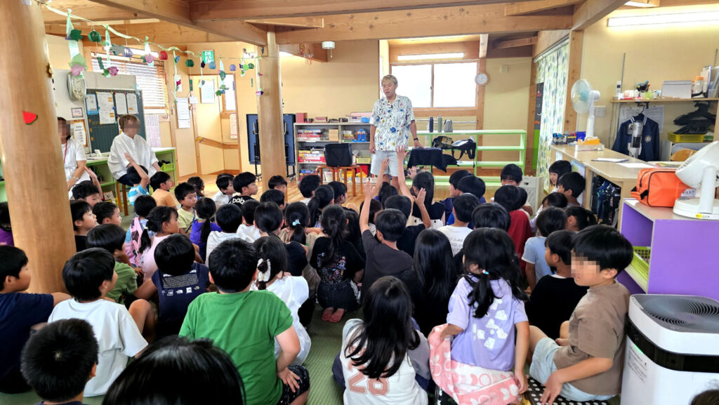 ALT案：
**学童イベント マジックショーの様子。富山市の学童保育で、多くの子どもたちが座って演者の話に耳を傾けている場面**
