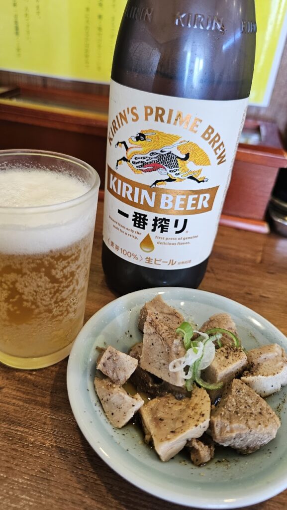 キリン一番搾りの瓶ビールと冷えたグラス、生ビールの隣に盛り付けられた黒胡椒風味の角切りチャーシュー小皿。快気祝いで味わった至福のセット。