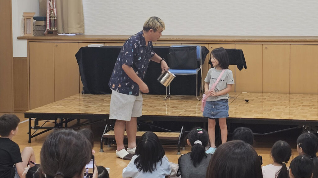 富山県南砺市の納涼祭マジックショーで子どもと一緒にステージを盛り上げる様子　古典マジック「マイザーズドリーム」を演じている。