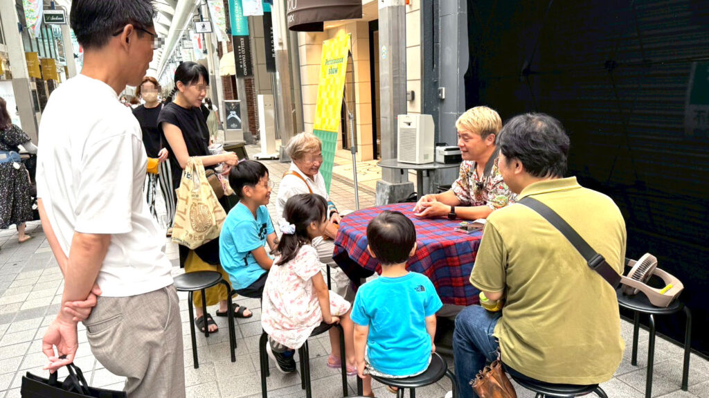 富山ストリートパフォーマンスでマジシャンが子どもや家族に囲まれカードマジックを披露している様子