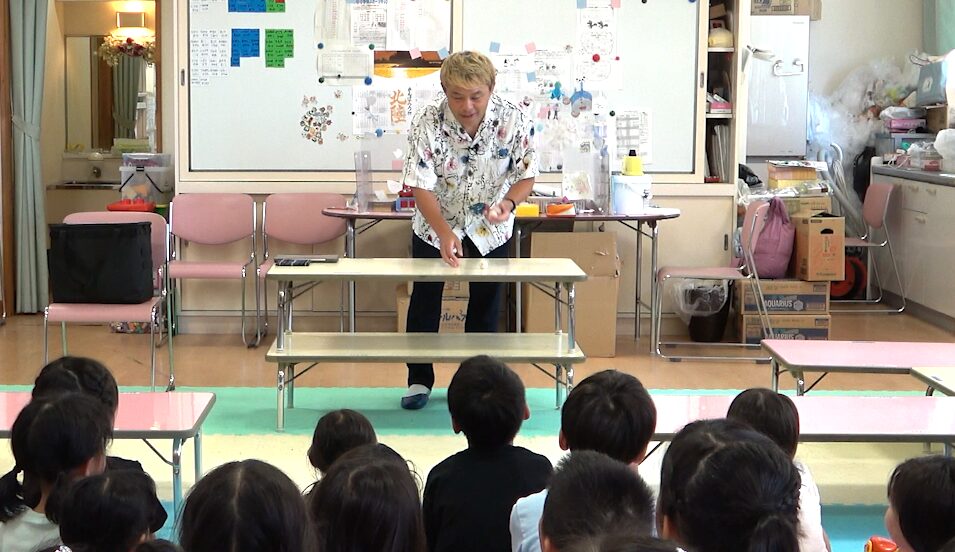 射水市の学童保育でマジックショーを披露するマジシャンコンプレッサーと見入る子どもたち