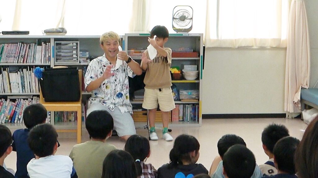 高岡市の学童保育でのマジックショー。子どもが前に出てコンプレッサーと一緒にマジックを楽しんでいる様子。