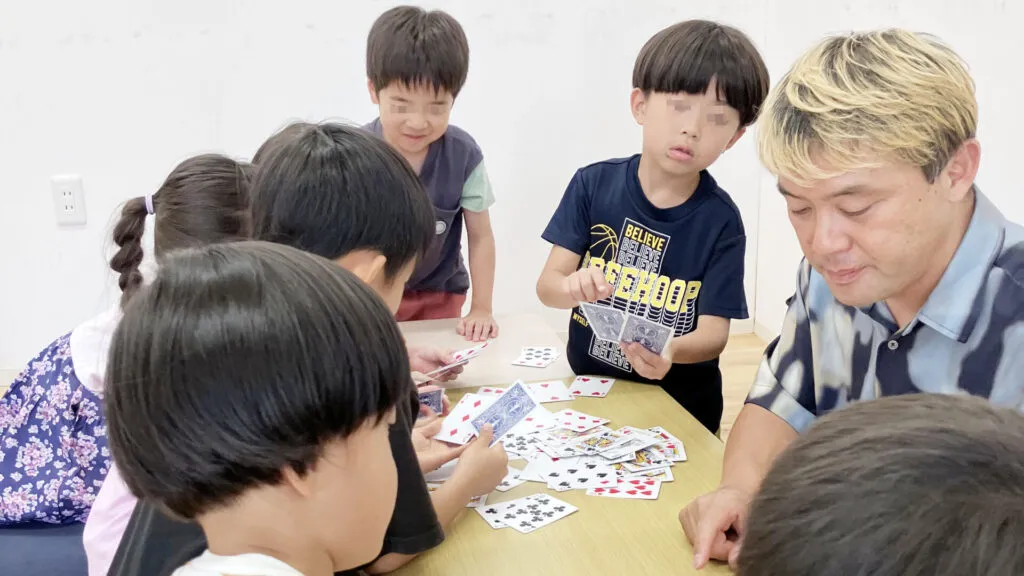 学童保育で子どもたちがカードマジックに挑戦する様子