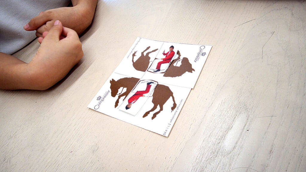 床に広げられたトリックアートのカード。馬に乗るマジシャンの絵が上下に分割されており、不思議な絵柄になっている。