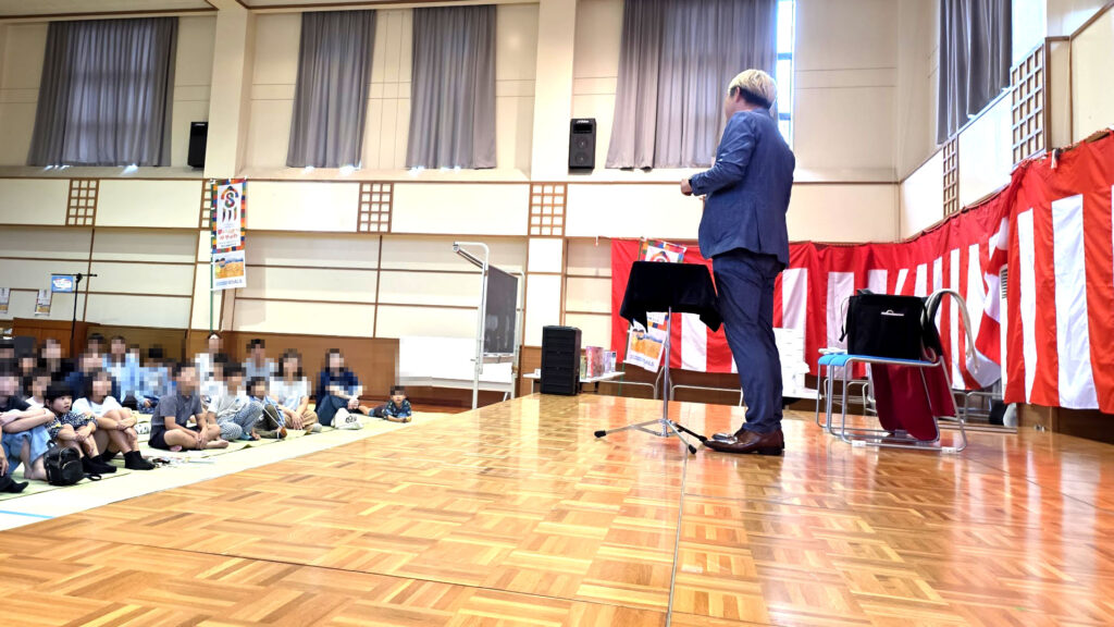 マジシャン コンプレッサーが富山のイベントステージに立ち、観客に語りかける横顔