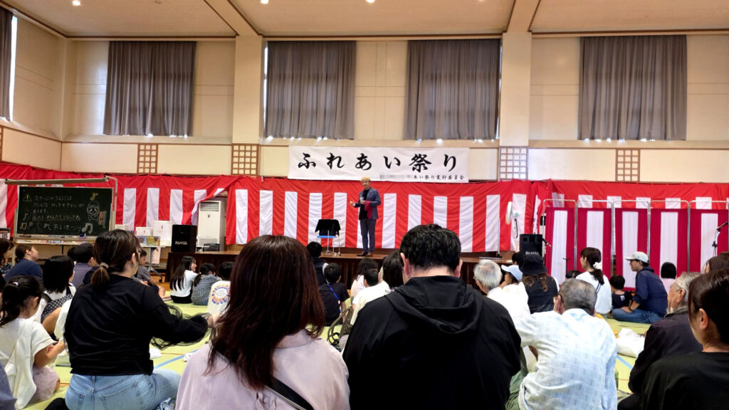 富山のイベント「ふれあい祭り」でマジシャン コンプレッサーのショーを観覧する大勢の観客の後ろ姿