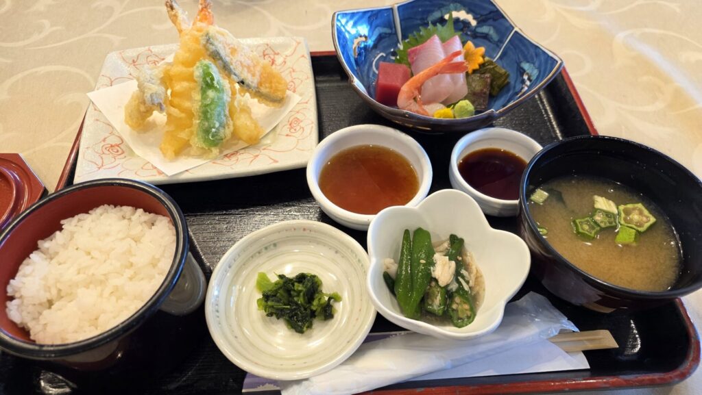 イベント会場で提供された和食御膳のアップ写真。お盆の上には、天ぷらの盛り合わせ、マグロや甘エビの刺身、ご飯、味噌汁、和え物などの小鉢が並んでいる。