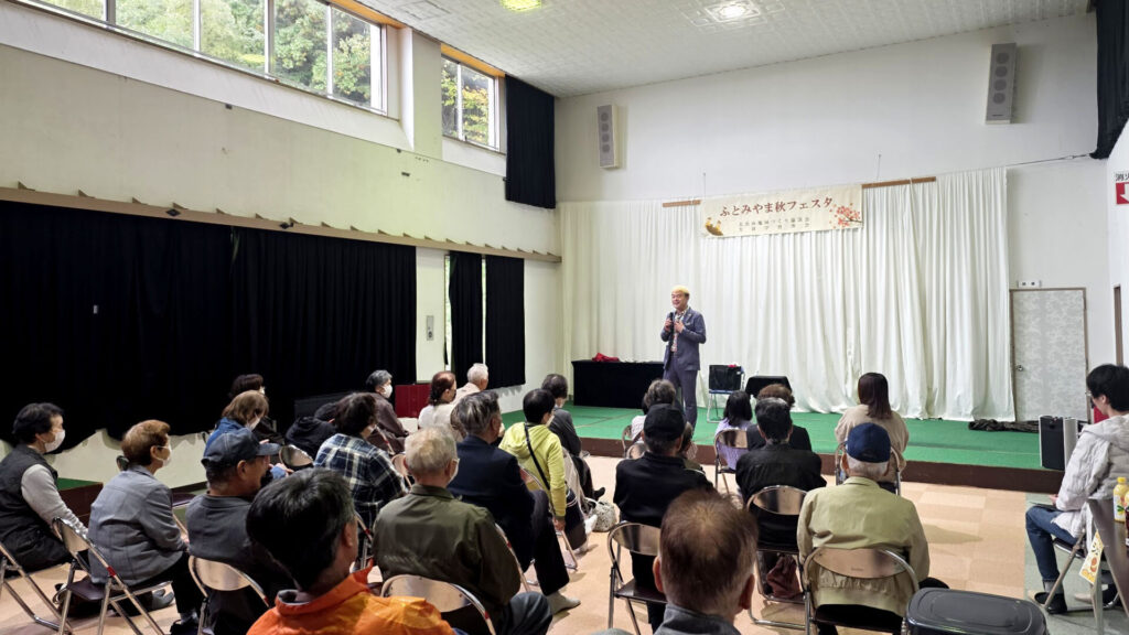 富山県南砺市「太美山秋フェスタ」時間を変更してまでの熱烈オファーに感謝 1 太美山秋フェスタの会場でマジックショーのオープニングトークをするコンプレッサーと満席の観客
