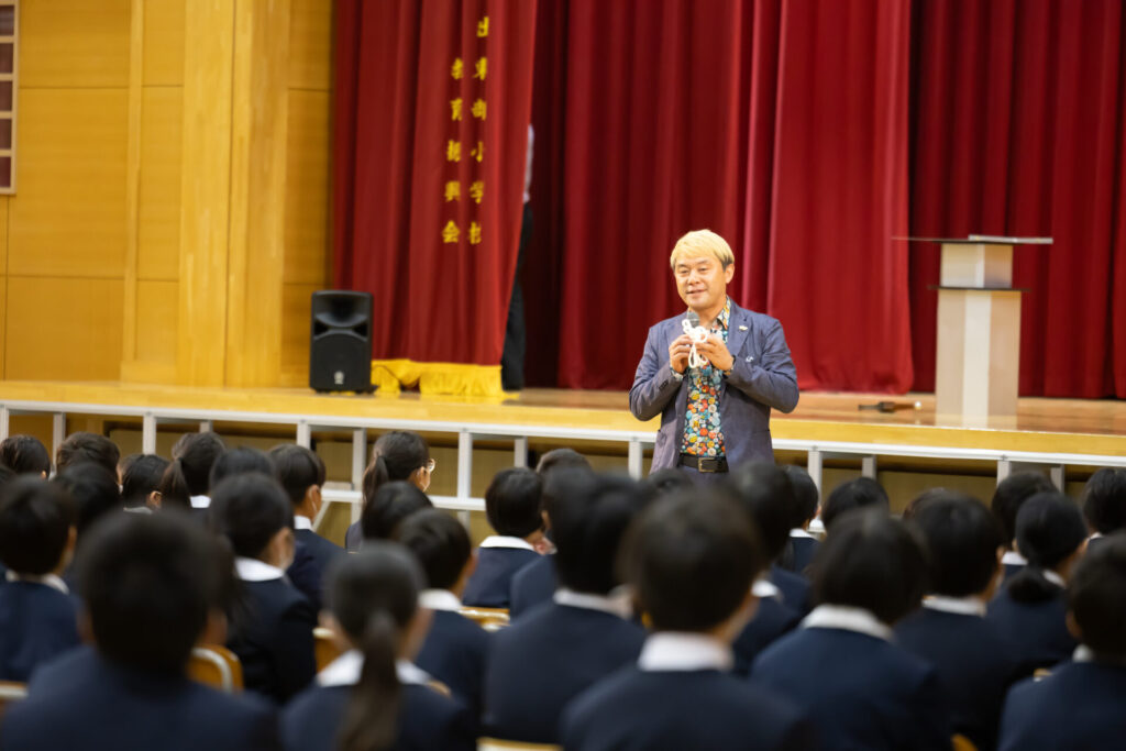  笑顔でマイクを持ち、子供たちとコミュニケーションを取りながら進めるトーキングマジック