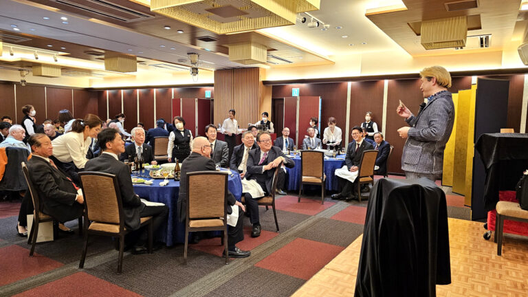 新年会で大勢の観客の前でステージマジックを演じるプロマジシャン コンプレッサー