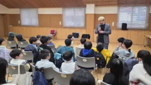 マイクを持って子供たちに語りかけるコンプレッサー。富山市のクリスマス会イベントで、マジシャンと子供たちが一体となって楽しんでいる様子