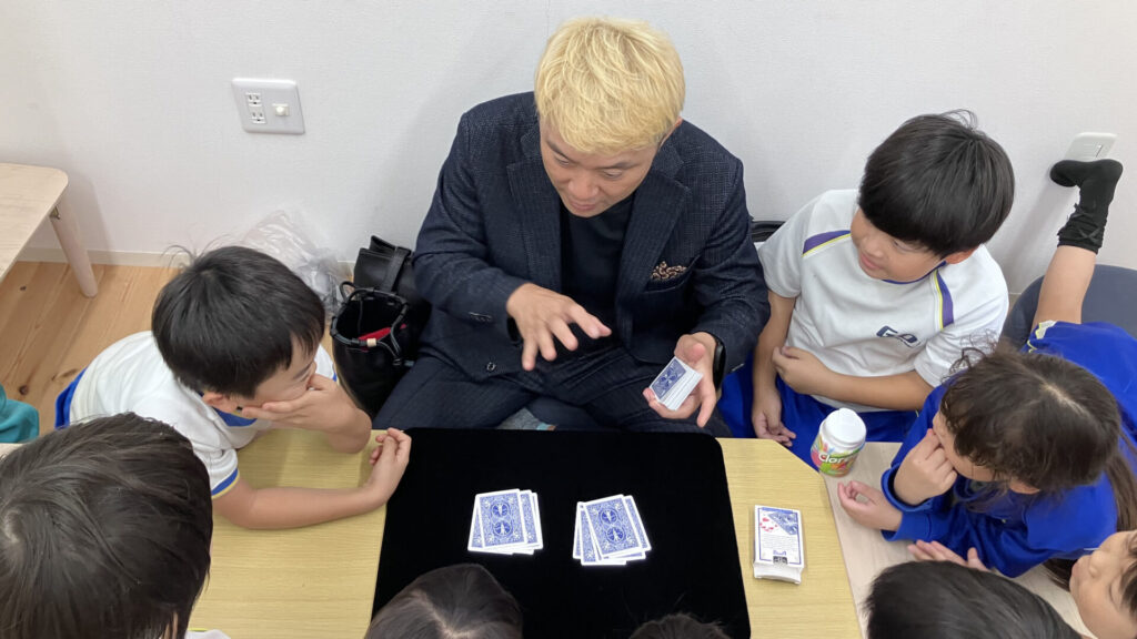 学童保育でマジックショーをするマジシャンと楽しんでいる子どもたち