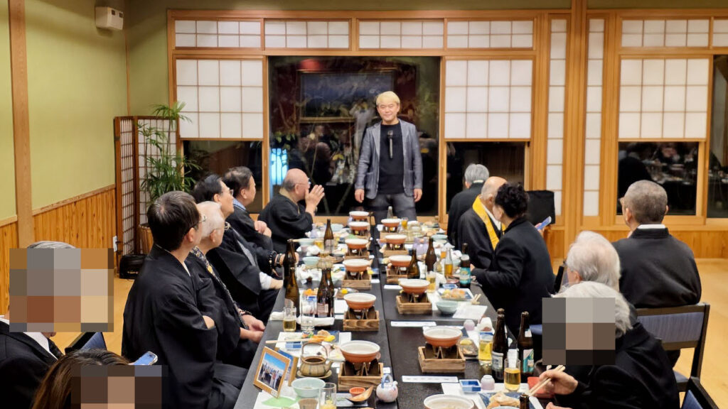 料亭「茜月」にて、先代御住職の三回忌法要後の会食でマジックを披露するコンプレッサー。御住職や参列者の皆様が間近で見守る温かい雰囲気。