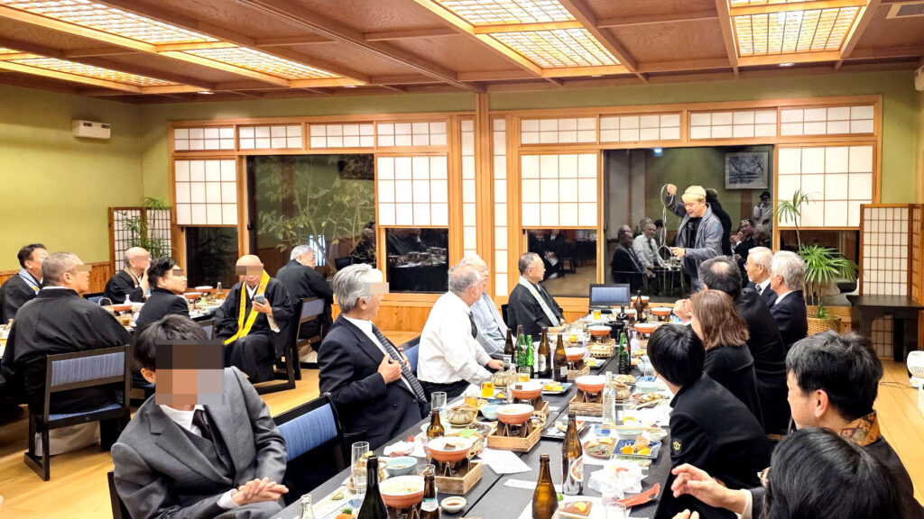 会場全体を見渡しながら、リングのマジックを披露するコンプレッサー。お子様から大人まで、幅広い世代の参列者がステージに注目している様子。