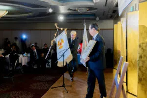 富山県倫理法人会 日本一祝賀会で県旗を掲げるマジシャン・コンプレッサー