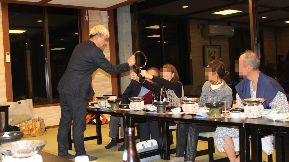 マジシャン・コンプレッサーが至近距離で披露する、チャイナリングのクロースアップマジック。大きなリングが重なり合う不思議な光景を、驚きを隠せないゲストのすぐ目の前で実演している様子。