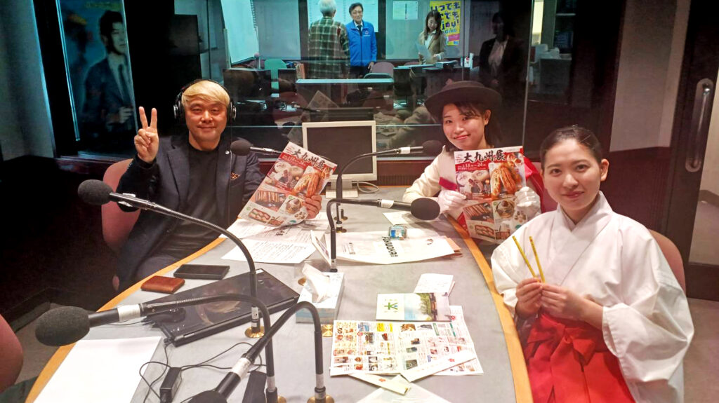 FMとやまスタジオでの収録風景。マジシャン・コンプレッサーがピースサインで笑顔、ちっご観光大使「恋姫」と太宰府天満宮の巫女が大九州展チラシを手に並ぶ
「しゃべっちゃお」収録完了！大九州展をPRするゲストのお二人と、笑顔いっぱいのスタジオにて