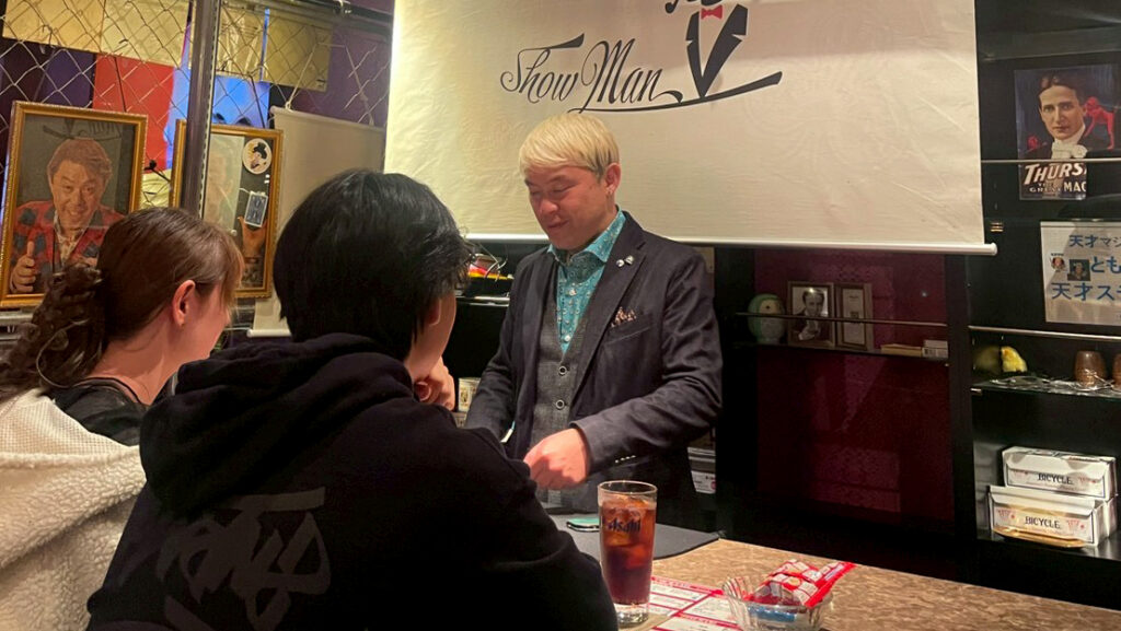 賑やかな富山の夜を楽しむお客様に囲まれながら笑顔でコミュニケーションをとるマジシャン・コンプレッサー