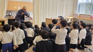 高岡市中田の学童保育でマジックショー 子どもたちが手を上げて盛り上がる様子