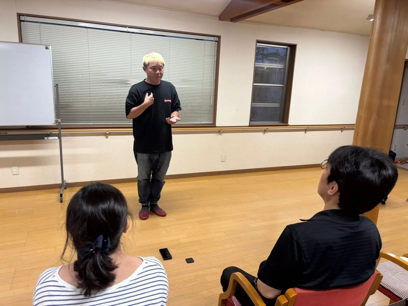 マジック研究会でスピーチを行うコンプオフィスの所属マジシャンと、聞き入るメンバー