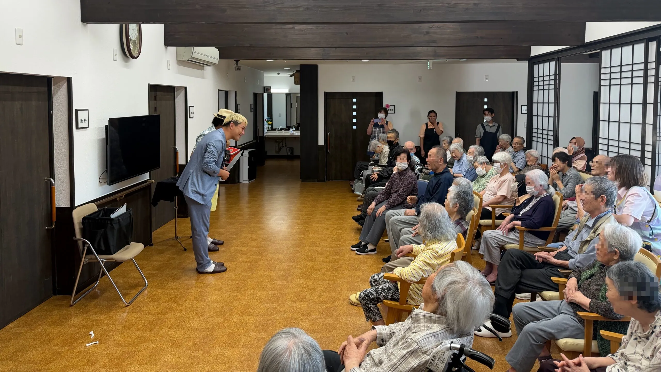 ケアホームなかそねの利用者さんに笑顔で語りかけながらご挨拶するマジシャン・コンプレッサー