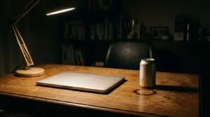 夜の仕事部屋の机。閉じたノートパソコンと飲みかけの缶ビール