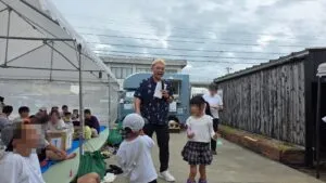 富山県砺波市の株式会社暮匠11周年感謝祭で、マイクを持って司会進行をするマジシャン・コンプレッサー