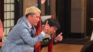 富山市倫理法人会20周年記念祝賀会で、ギロチンのマジックのアシスタントを務めた男性とサムズアップを交わすマジシャン・コンプレッサー