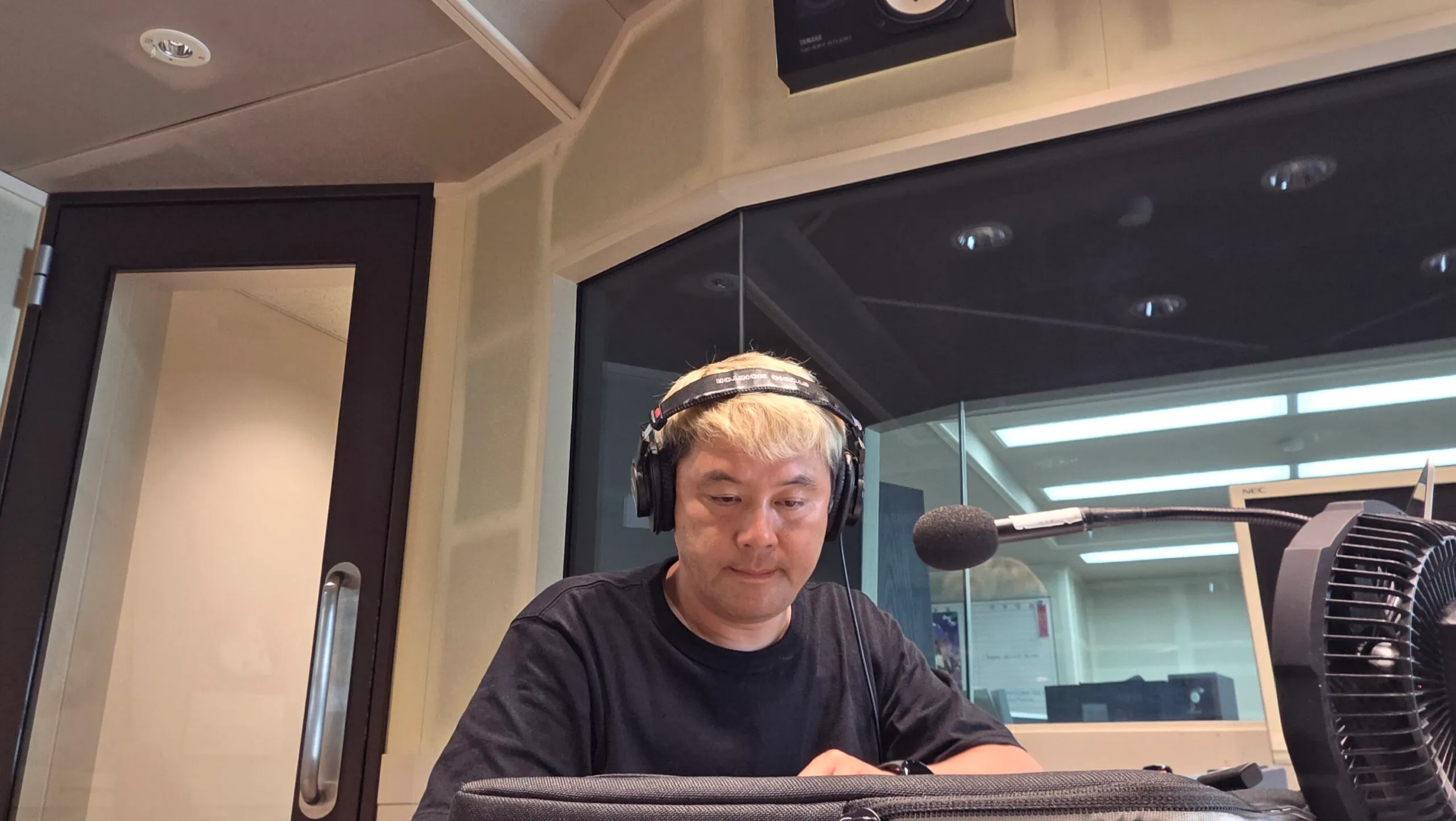 FMとやまのスタジオでヘッドホンを着け、マイクの前で収録に臨むマジシャン・コンプレッサー