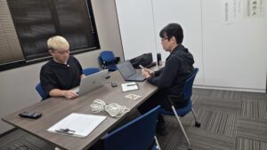 AIエージェント講座のリハーサル。ノートパソコンに向かうマジシャン・コンプレッサーと、スマホを手に生徒役をつとめるマーサさん