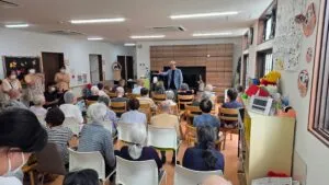 ケアホームあきもとの介護施設マジックショーで利用者さんに語りかけるコンプレッサー