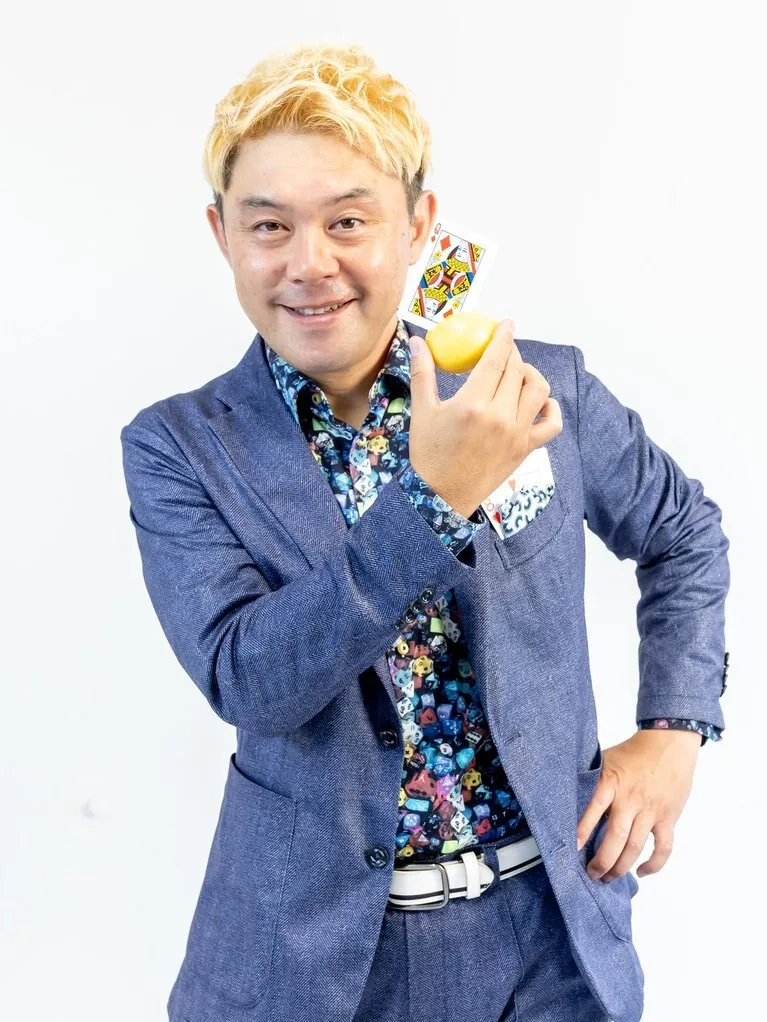 マジシャン コンプレッサー。トランプとレモンを手にして笑顔で立つ富山のプロマジシャン