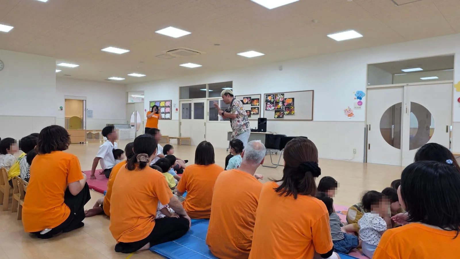 富山市の保育園のプレイルームでマジックを演じるマジシャン・コンプレッサーと見入る園児さんや先生方
