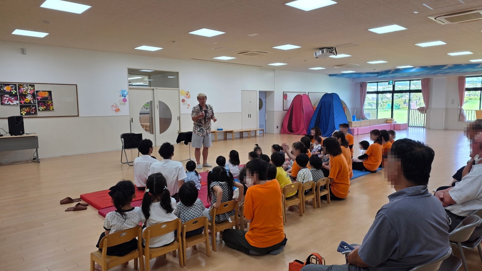 保育園のマジックショーは0歳から楽しめる|富山市で約30分 3 富山市の保育園のプレイルームで来賓の皆さまや先生方と一緒に園児さんがマジックショーを見ている様子