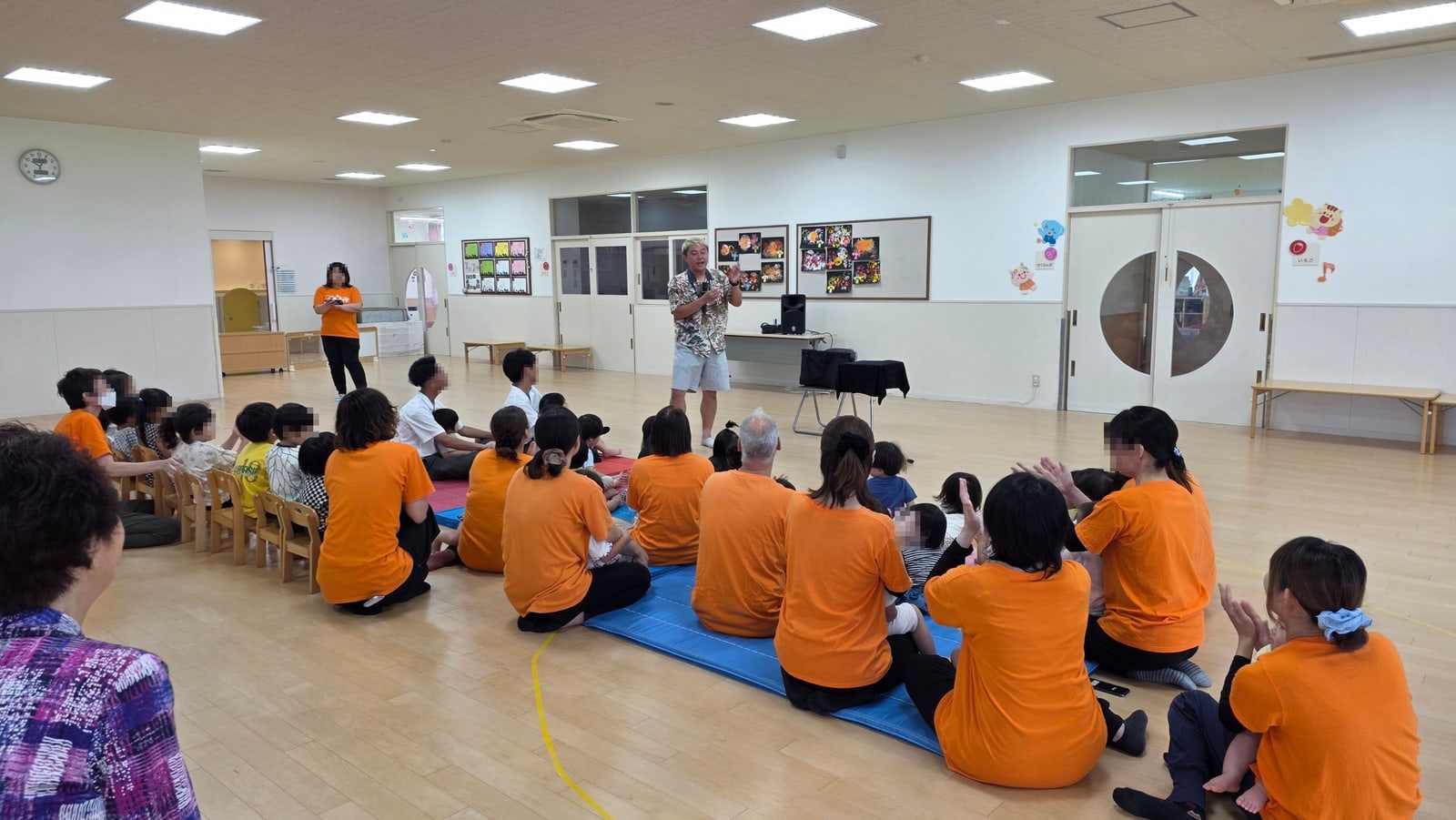 保育園のマジックショーは0歳から楽しめる|富山市で約30分 4 富山市の保育園のプレイルームで園児さんと先生方が拍手をしながらマジックショーを見ている全景