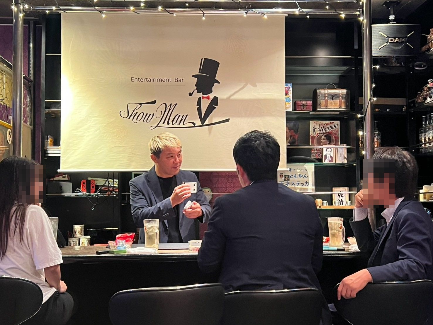 富山桜木町 マジックバー ショーマン|2週続けて出演、20年前の夢が"ホーム"になった夜 4 マジックバー ショーマンのカウンターで、コインとカードを見せながらお客さまに語りかけるマジシャン・コンプレッサー