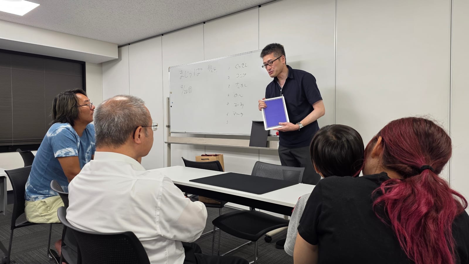 富山のマジックサークルを見学したご家族の夜|まじっぱ8月24日レポート 1 ホワイトボードを背に紫のカードを見せるマジシャン・コンプレッサーと見学のご家族|富山マジックサークルまじっぱ8月24日