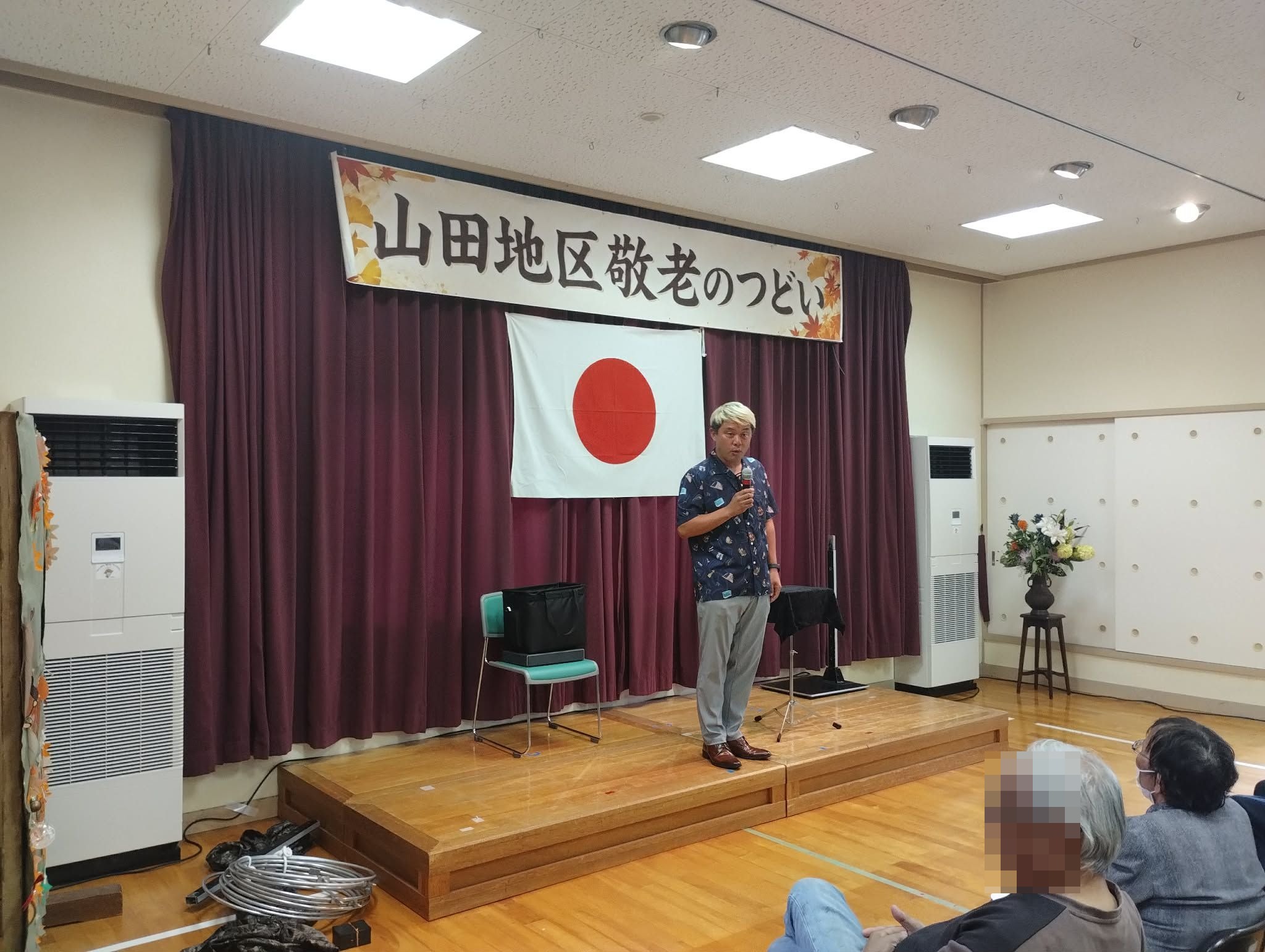 南砺市の敬老会でマジックショー|2年ぶり、2回目も盛り上がりました! 3 南砺市の敬老会マジックショーで客席の近くから話しかけるコンプレッサー