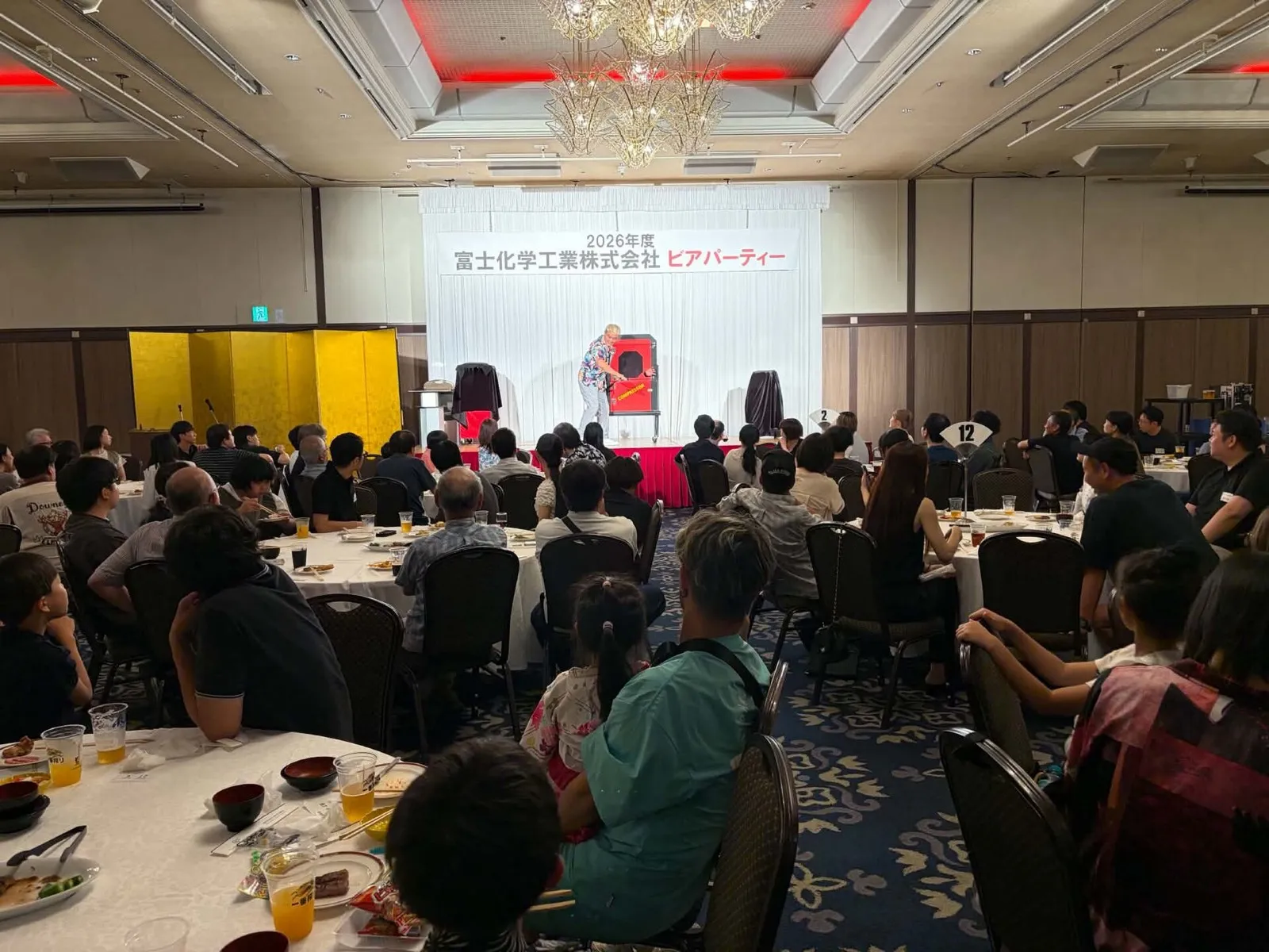 ホテル宴会場のステージで大型イリュージョンを演じるマジシャン