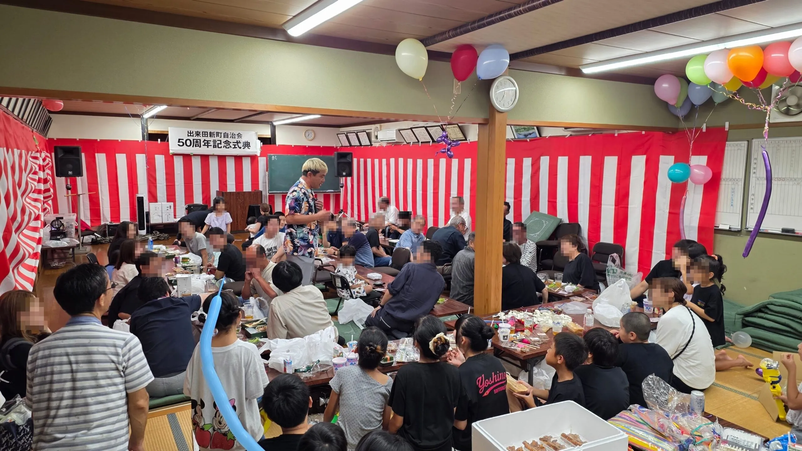 高岡市の公民館でマイクを持ち卓のそばで話すコンプレッサー