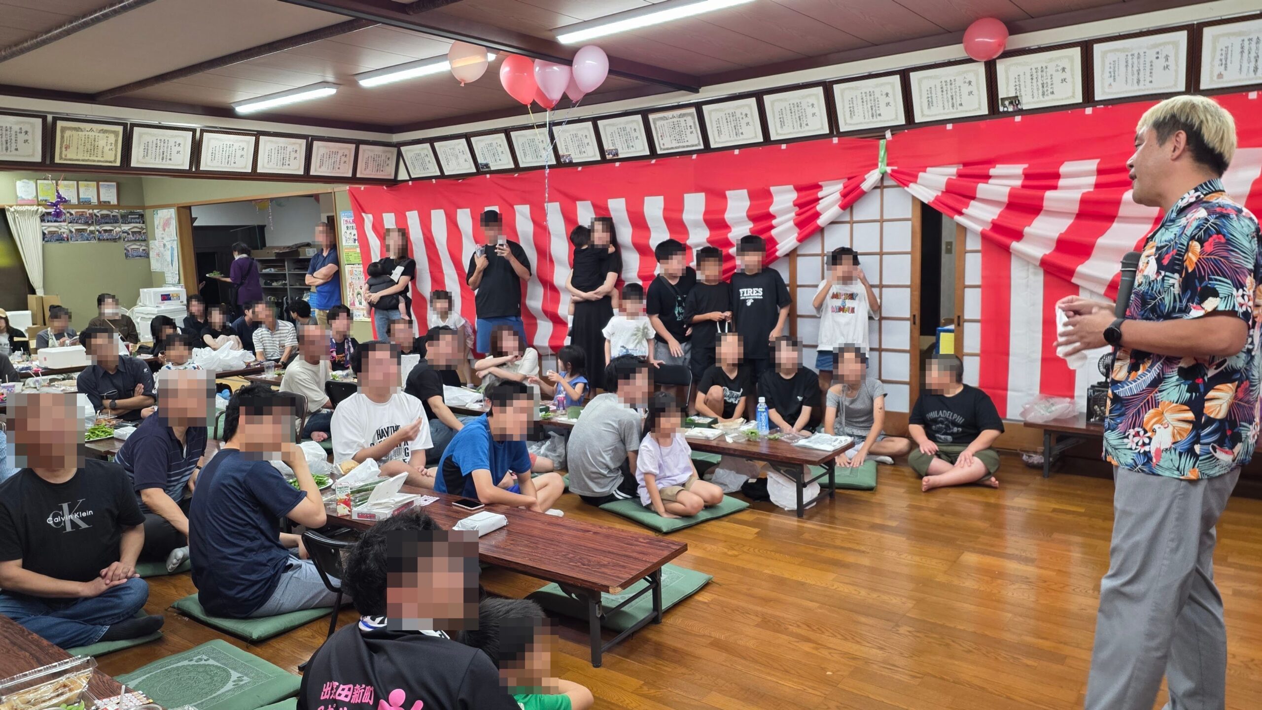 高岡市の納涼祭でマジックショー|50周年のお祝いと懐かしい再会 4 公民館の室内でマジックを披露するコンプレッサーを見守る子どもと大人たち