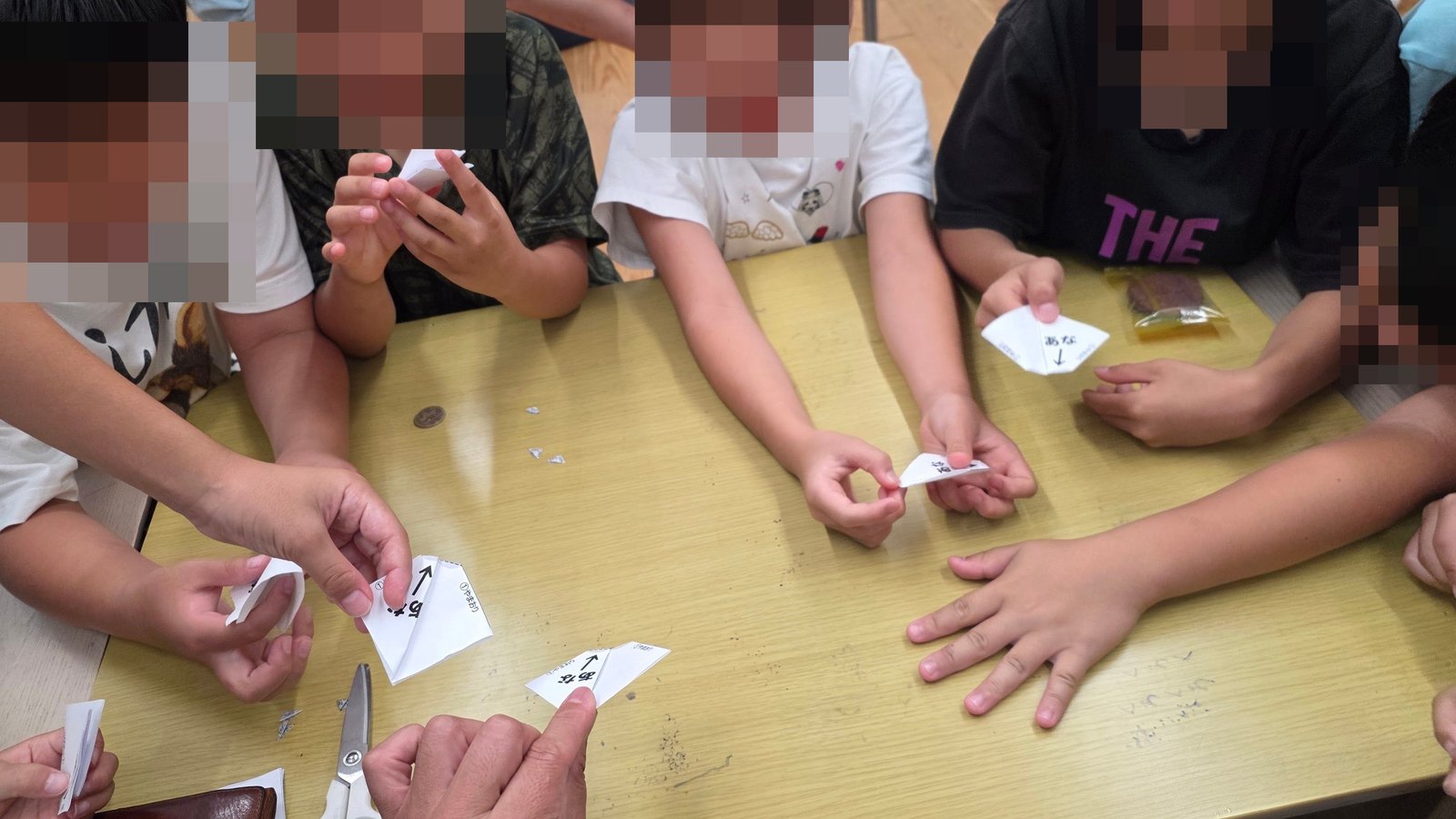 紙を折りながら山折り谷折りに取り組む学童保育の子どもたちの手元