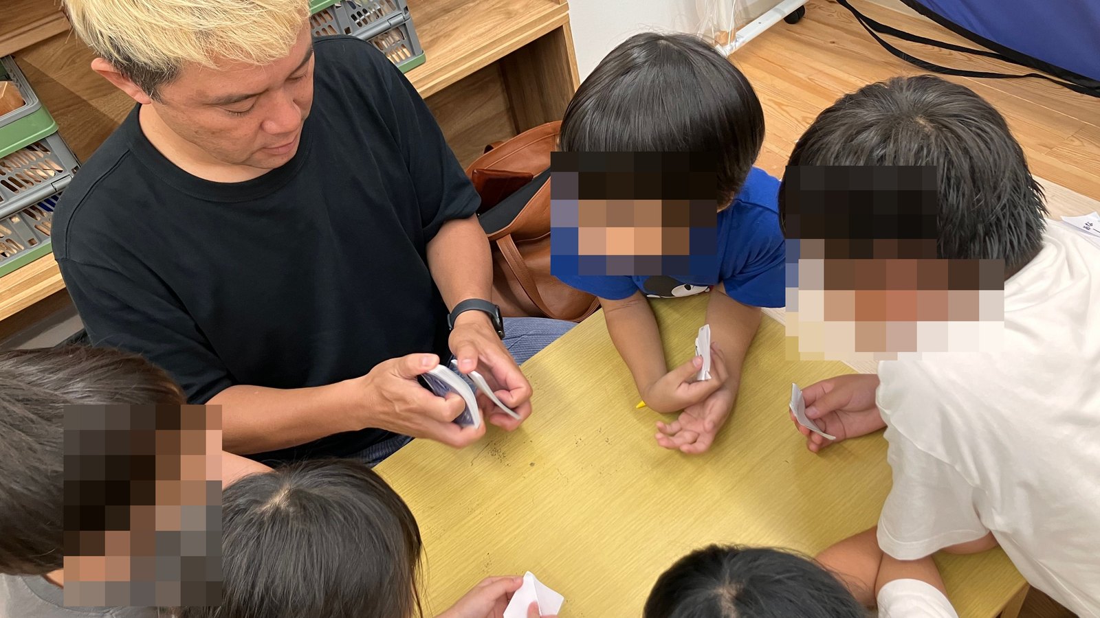トランプを使ったマジックをのぞき込む学童保育の子どもたち