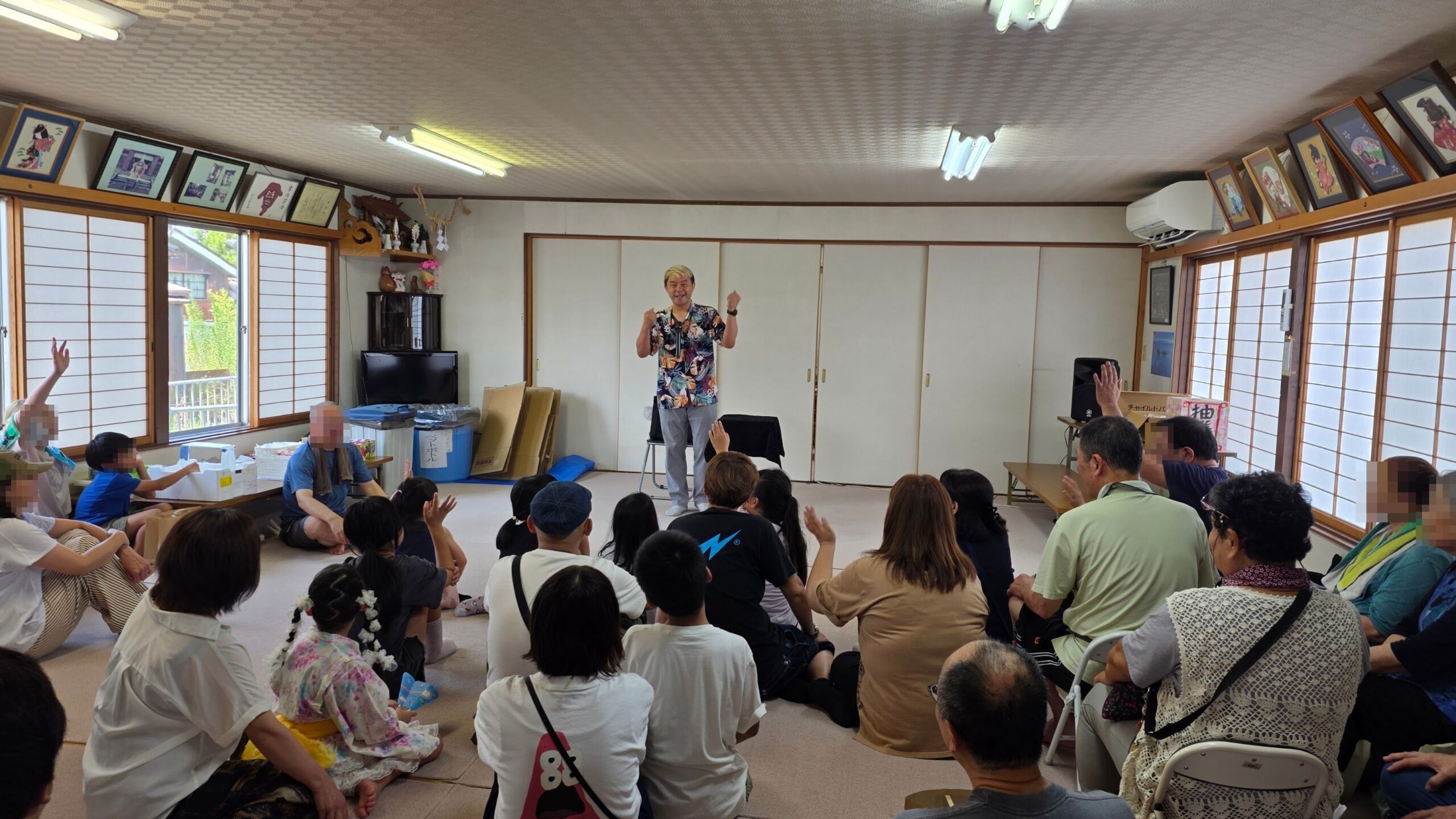 富山市新庄町の夏祭りで手を挙げる子どもと大人にマジックショーを披露するコンプレッサー