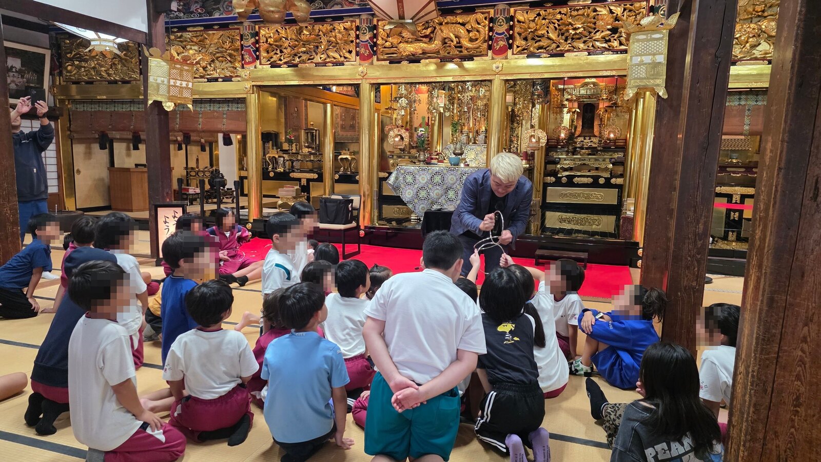 射水市のお寺の本堂で、子どもたちの目の前に出てリングのマジックを見せるコンプレッサー
