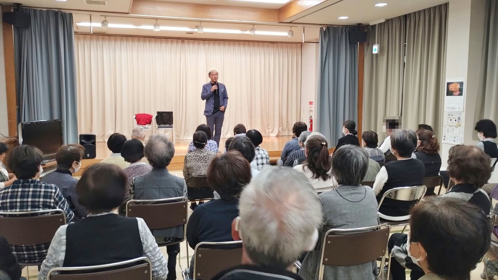 いきいきサロンのマジックショーで、マイクを持って客席の皆さんに話しかけるコンプレッサー