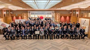 「富山県 高岡市中央準倫理法人会 開設式典」の看板の下で、前列中央に認可書の額を掲げ、会員と来賓が並んだ集合写真
