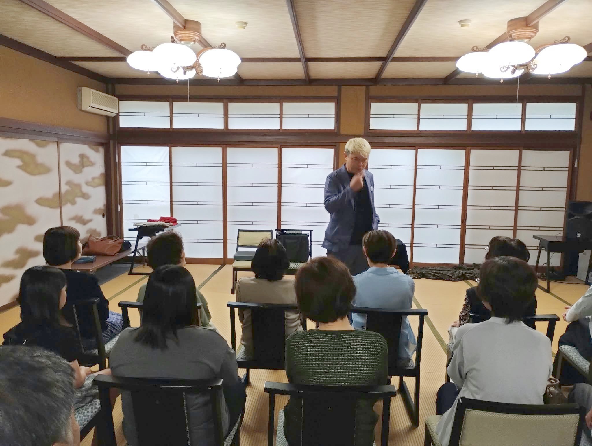 高岡市福岡町の町内会マジックショーで、口元に手を当てて考えこむコンプレッサー